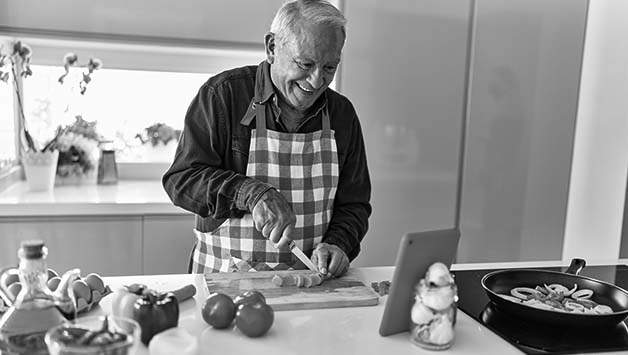 older man chopping carrots on counter