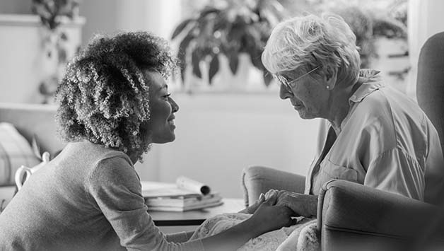 aide holding senior womans hands
