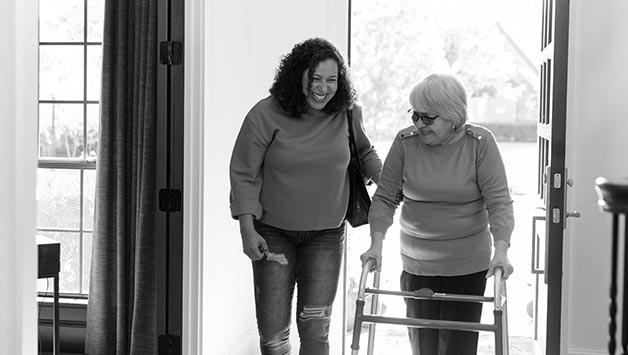 adult daughter helping mom with walker through front door