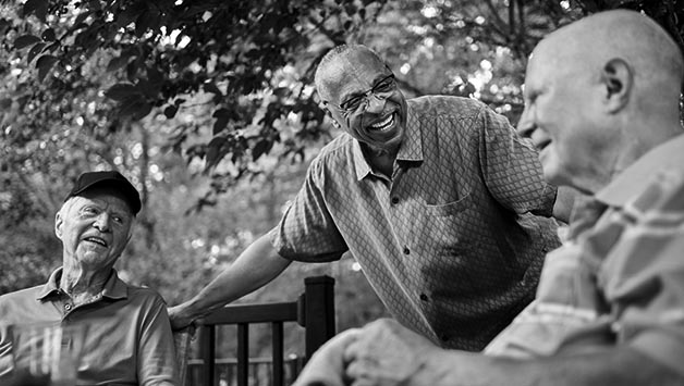 senior men talking outside sitting down